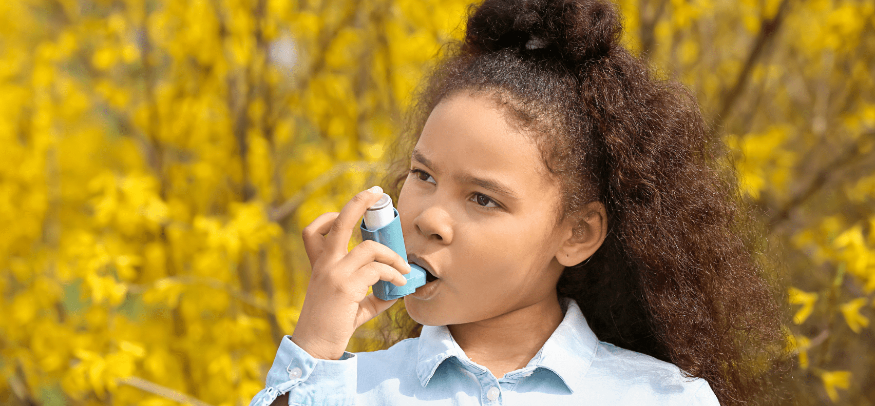 girl using her inhaler to treat her asthma